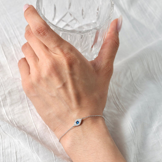 Close-up of a woman wearing the Awakened Time Evil Eye Bracelet featuring a blue gemstone eye charm on a delicate sterling silver chain.