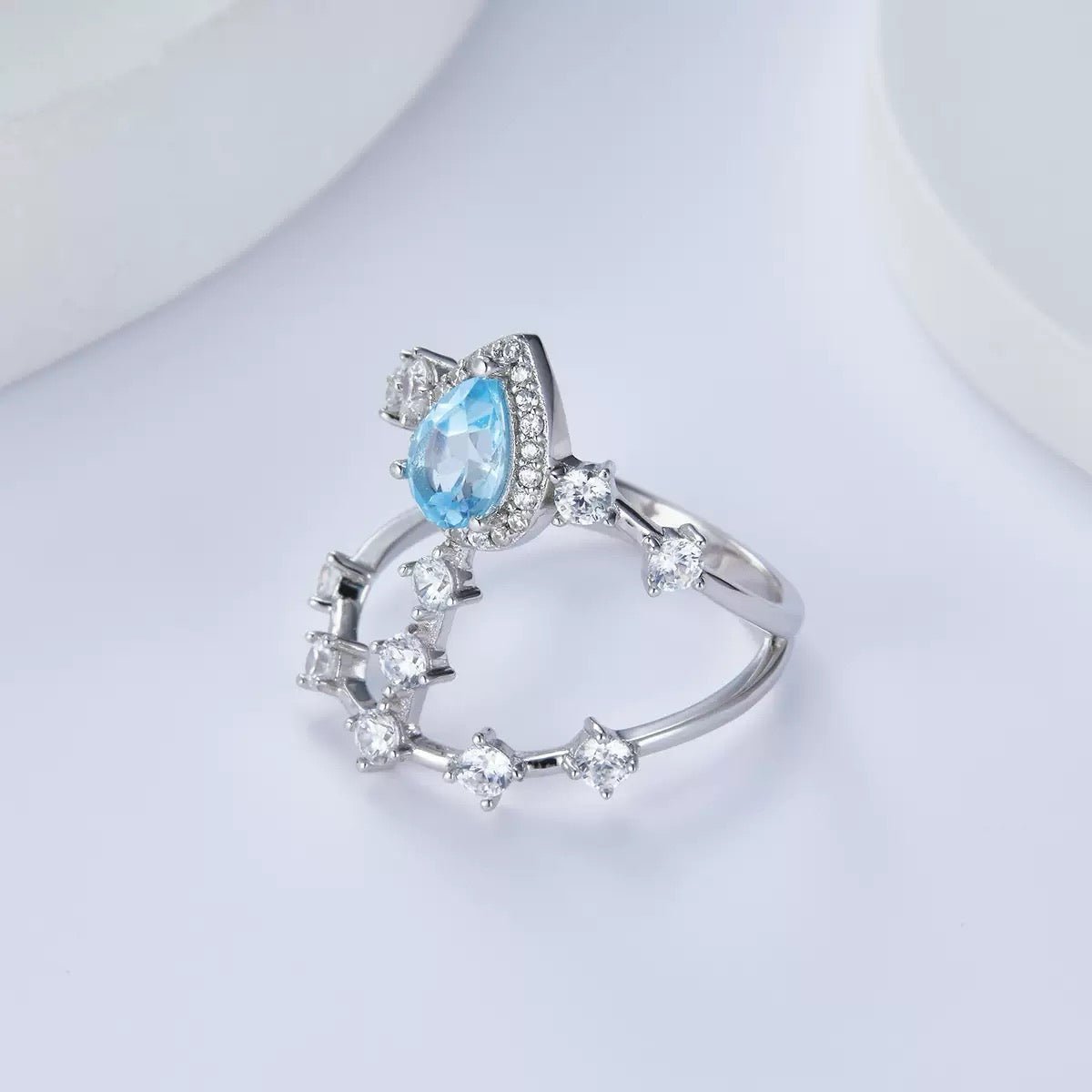 wakened Time Sky Vault Ring angled product shot, displaying the unique architectural openwork band adorned with a pear-cut blue topaz and sparkling cubic zirconia stones.