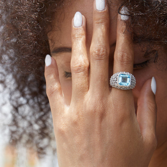 Close-up lifestyle portrait of a model wearing the Awakened Time Glacier Crown Ring featuring a radiant blue topaz center stone set in 18ct white gold vermeil.