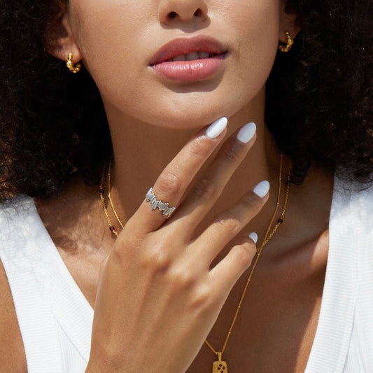 Editorial lifestyle portrait of a model wearing the Awakened Time Silver Shard Irregular luxury ring with a sculptural jagged silhouette, set in 18ct white gold vermeil and styled with complementary gold jewelry.