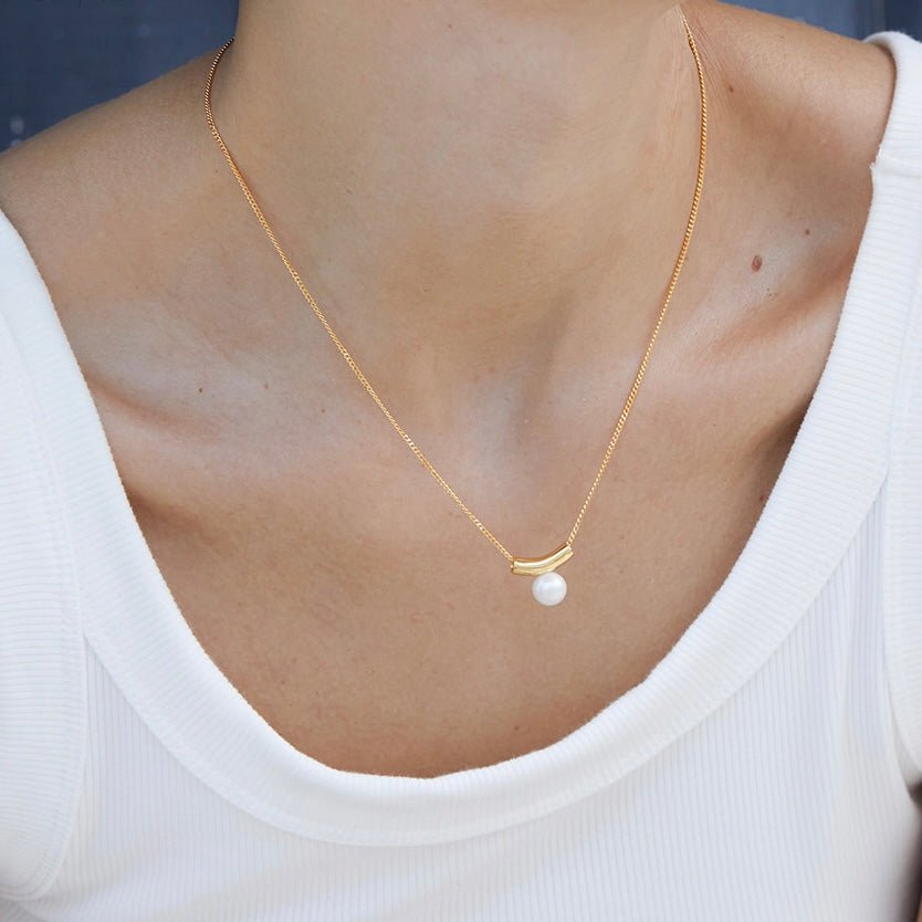 Portrait of a model wearing the minimalist Arc de Lune gold vermeil freshwater pearl necklace by Awakened Time.