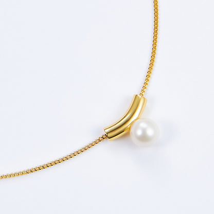 Macro detail showing the smooth gold vermeil arc holding a luminous freshwater pearl on the Arc de Lune necklace.