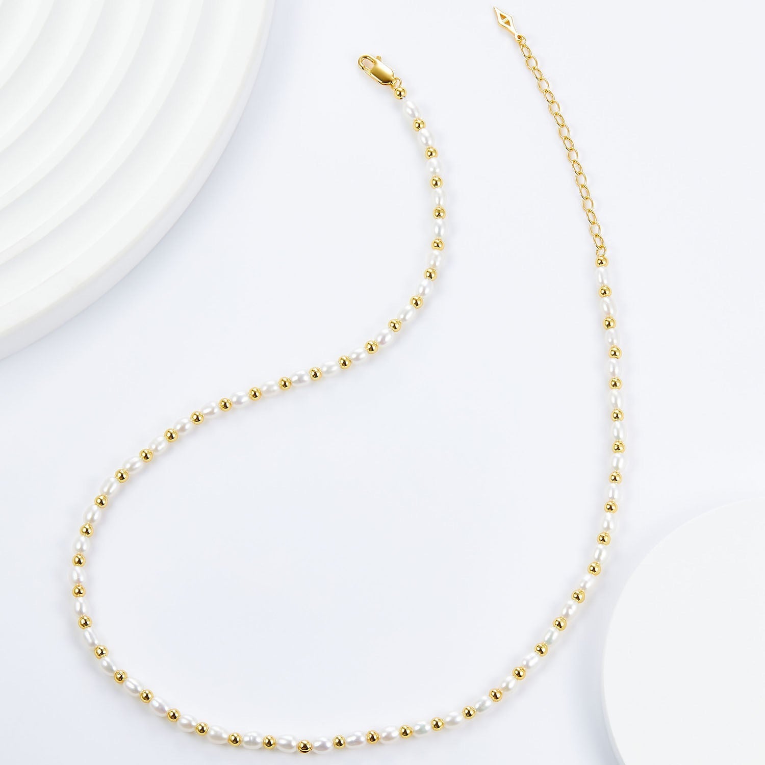Overhead view showing the complete Bare Luxe Golden Pearl Necklace layout with gold chain and clasp.