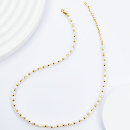 Overhead view showing the complete Bare Luxe Golden Pearl Necklace layout with gold chain and clasp.