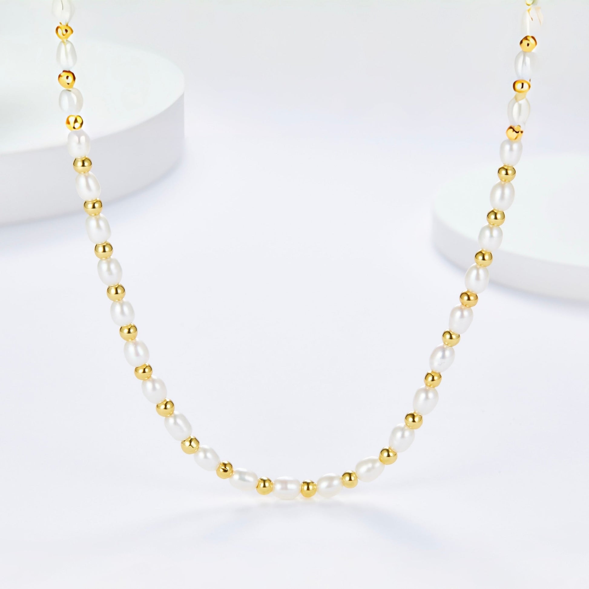Full view of the Bare Luxe Golden Pearl Necklace laid out on a white surface.