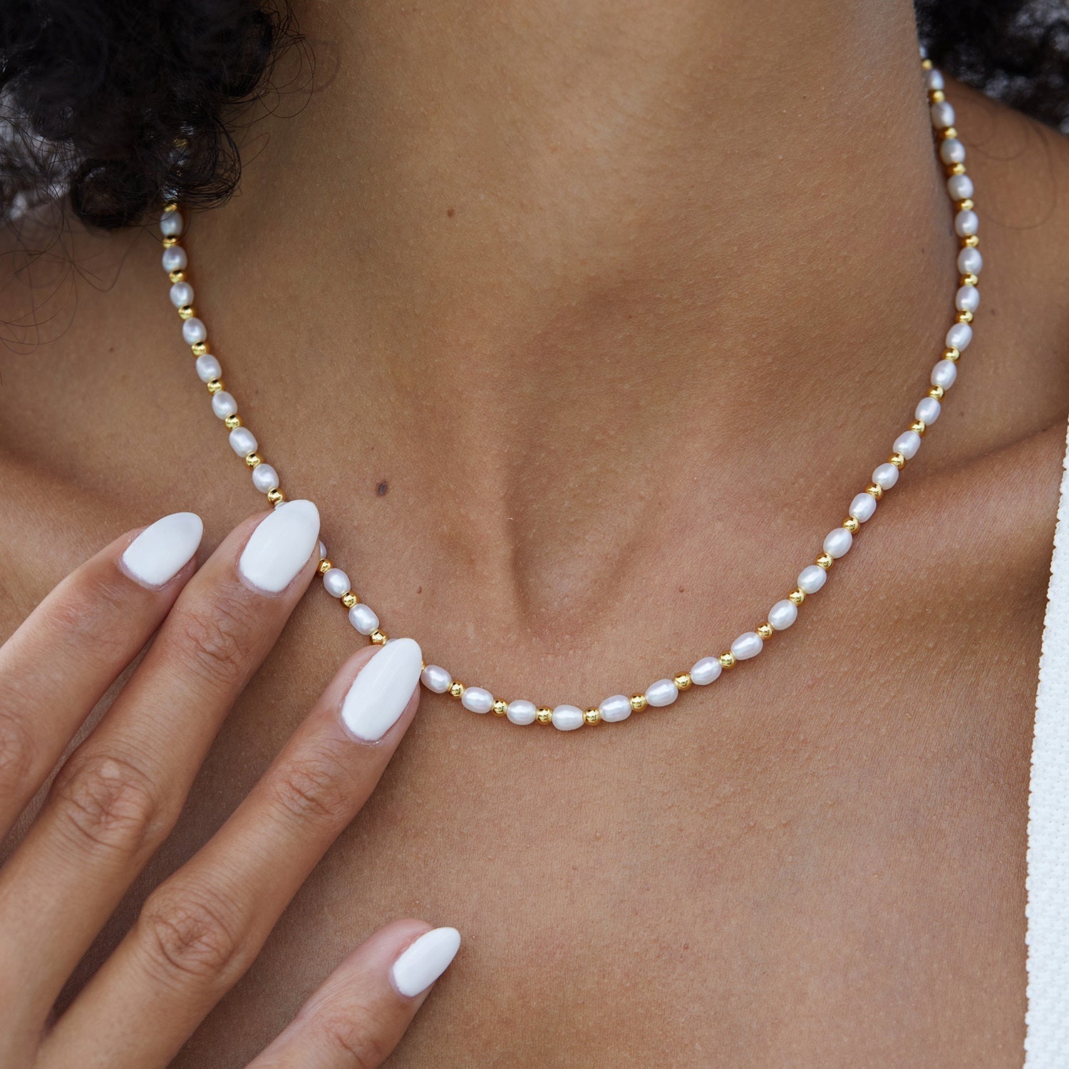 Model wearing the Awakened Time Bare Luxe Golden Pearl Necklace featuring freshwater pearls and gold beads.