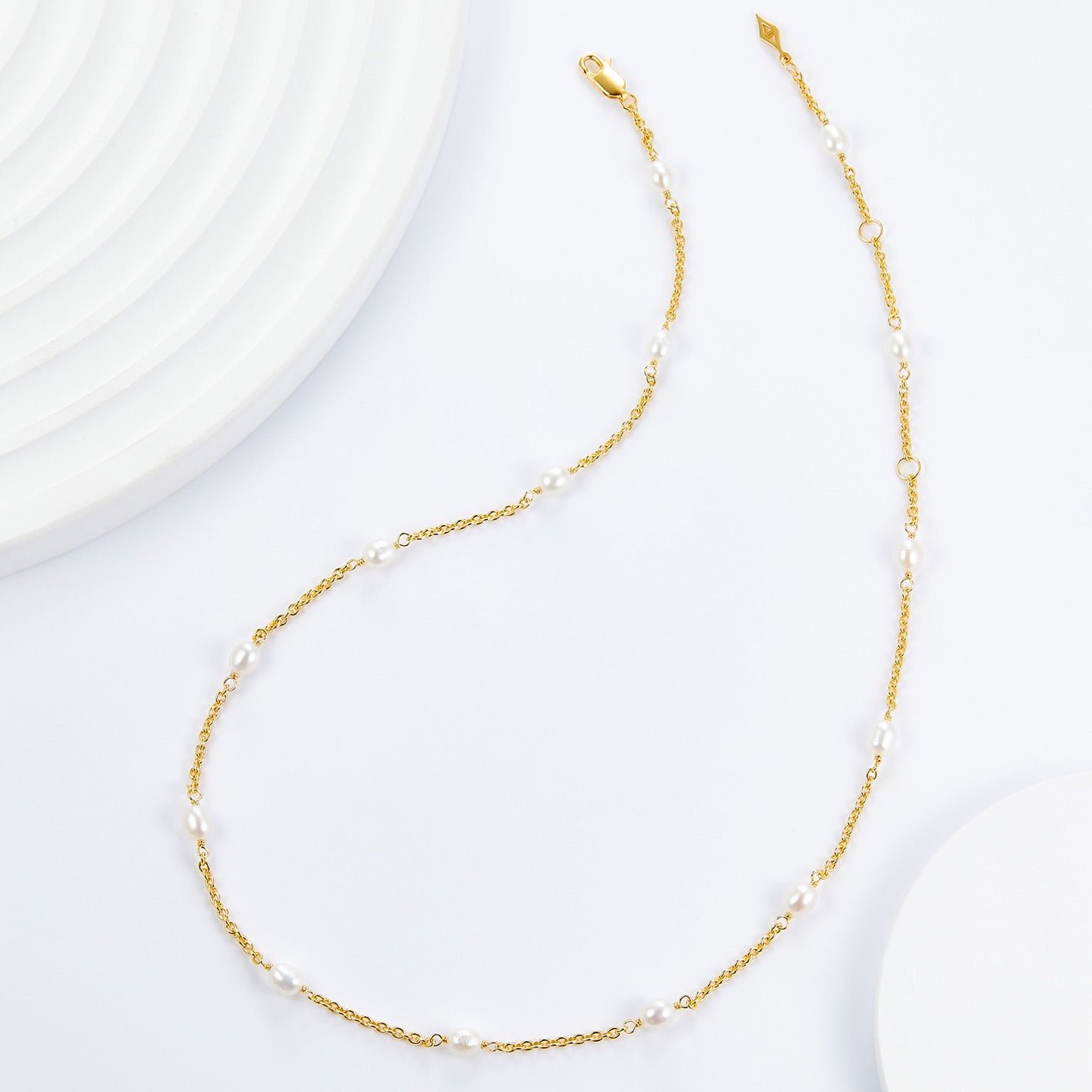 Flat lay of the complete Awakened Time Bare Luxe Orbit gold chain necklace displaying the evenly spaced freshwater pearls.