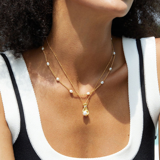 Model wearing the Awakened Time Bare Luxe Orbit pearl chain layered with a gold pendant necklace.