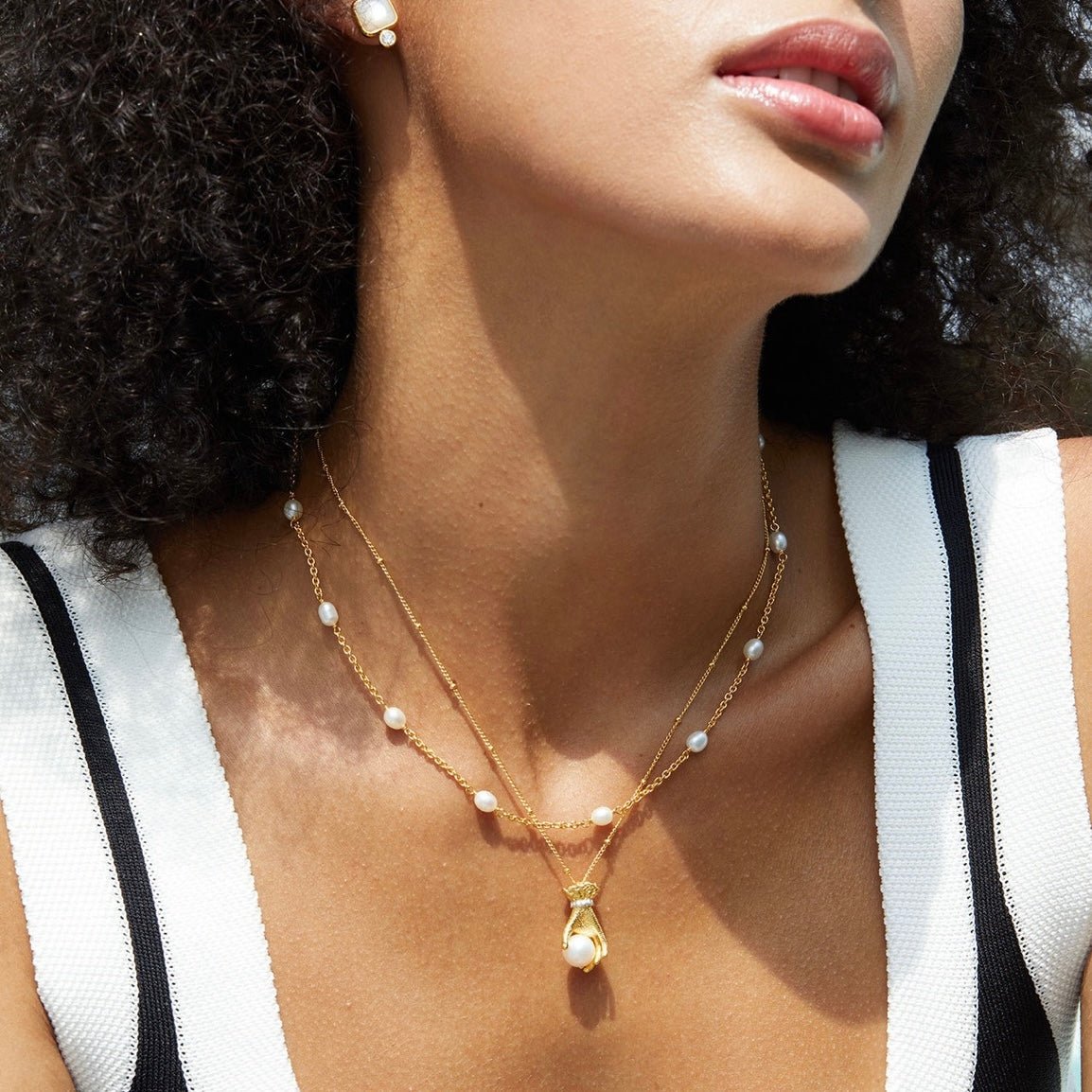 Close-up portrait of a model wearing the gold and freshwater pearl Bare Luxe Orbit necklace by Awakened Time.