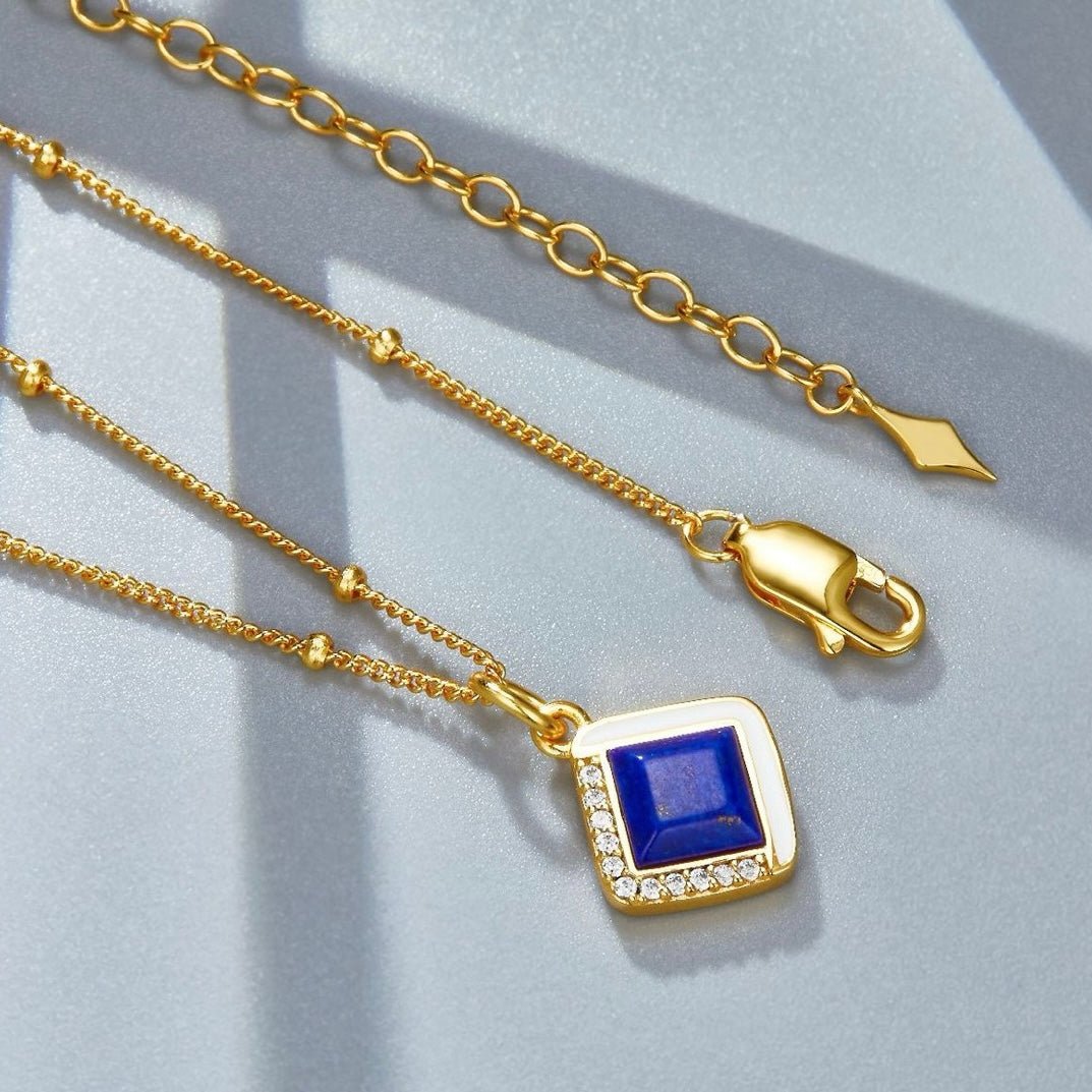 Macro view of the gold beaded chain layout, lobster clasp, extension, and square lapis lazuli pendant for the Bleu Intuition necklace.