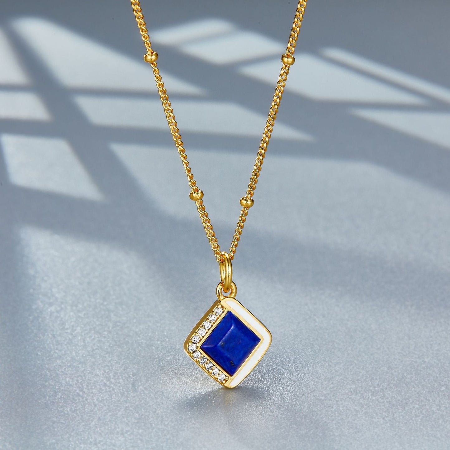 Angle view of the Awakened Time Bleu Intuition lapis lazuli pendant hanging on its gold chain.
