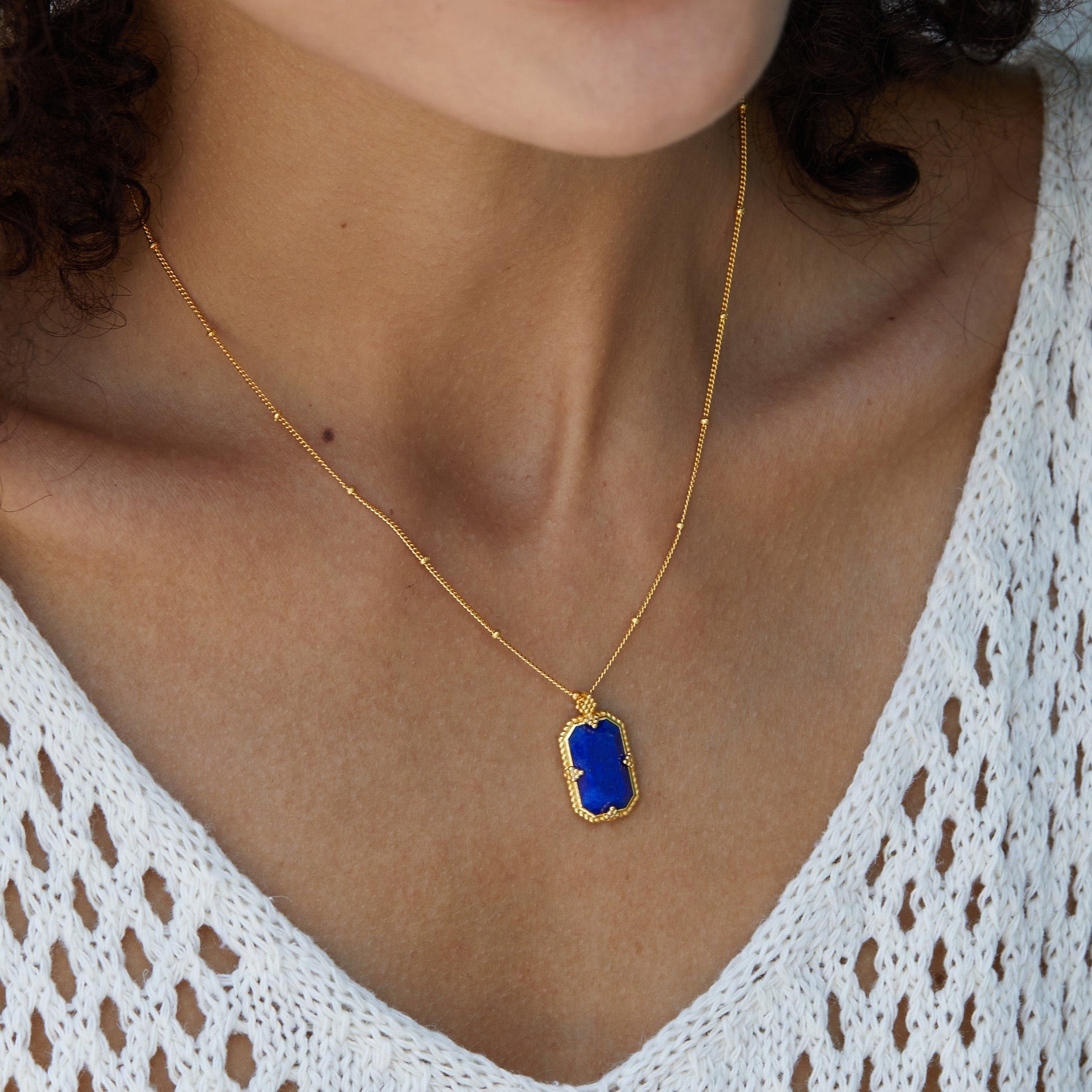 Close-up profile of a model showcasing the Awakened Time Bleu Nuit gold and lapis lazuli pendant.