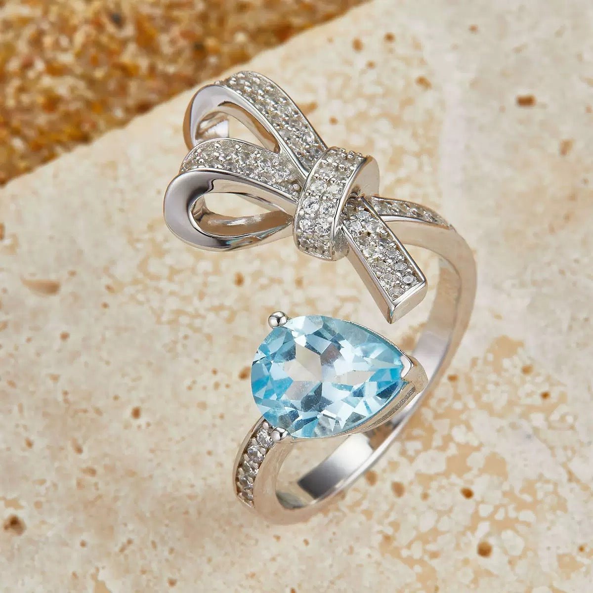 Awakened Time Bleu Ruban Ring featuring a natural blue topaz gemstone and pavé cubic zirconia ribbon design in 18ct recycled white gold vermeil over sterling silver.