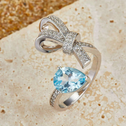 Awakened Time Bleu Ruban Ring featuring a natural blue topaz gemstone and pavé cubic zirconia ribbon design in 18ct recycled white gold vermeil over sterling silver.