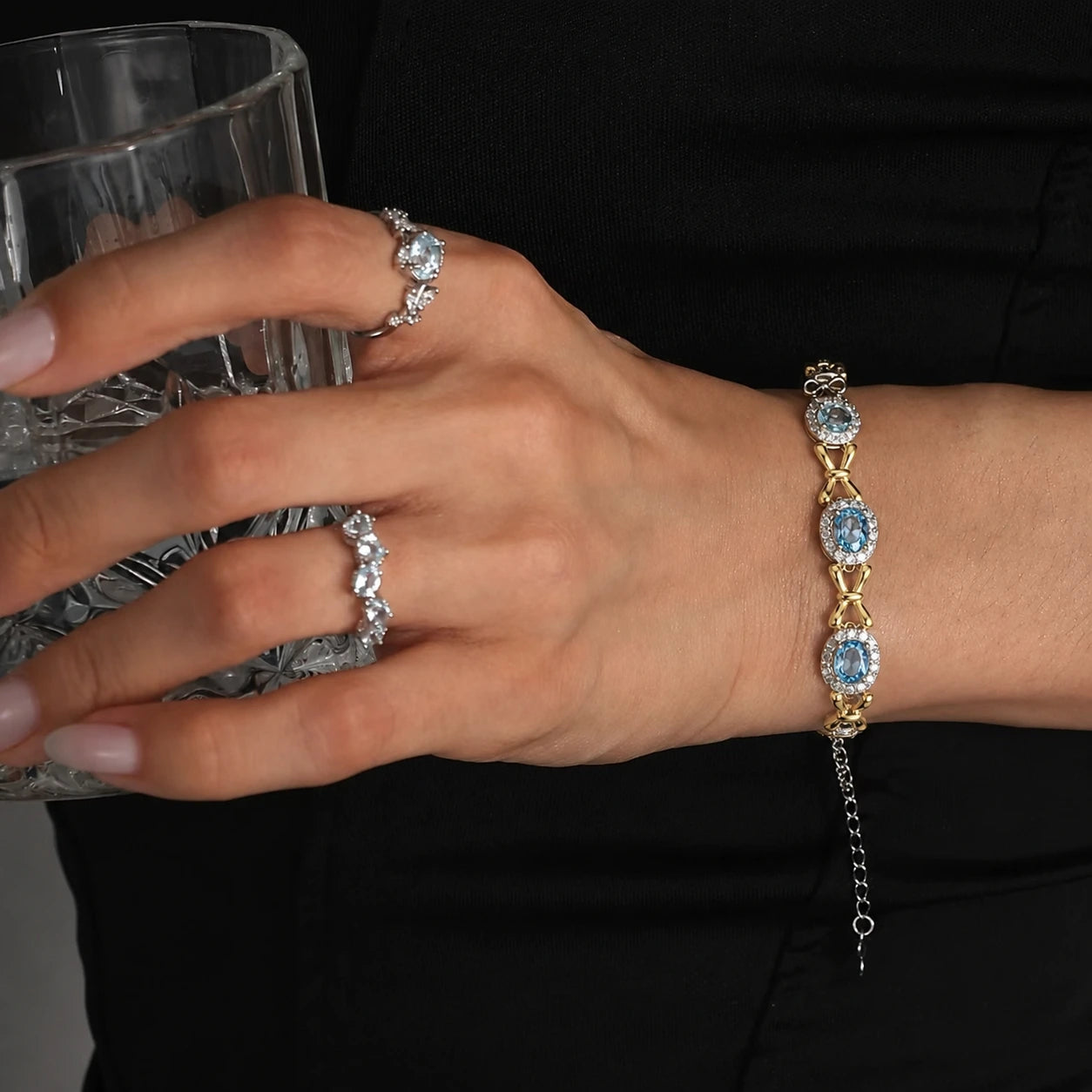 Woman wearing the Awakened Time Bluelace Bracelet featuring gold tone S925 sterling silver and four natural blue topaz gemstones.