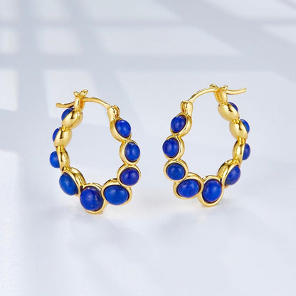 Front view flat lay of Awakened Time Céleste 18ct gold vermeil hoop earrings with natural blue lapis lazuli stones.