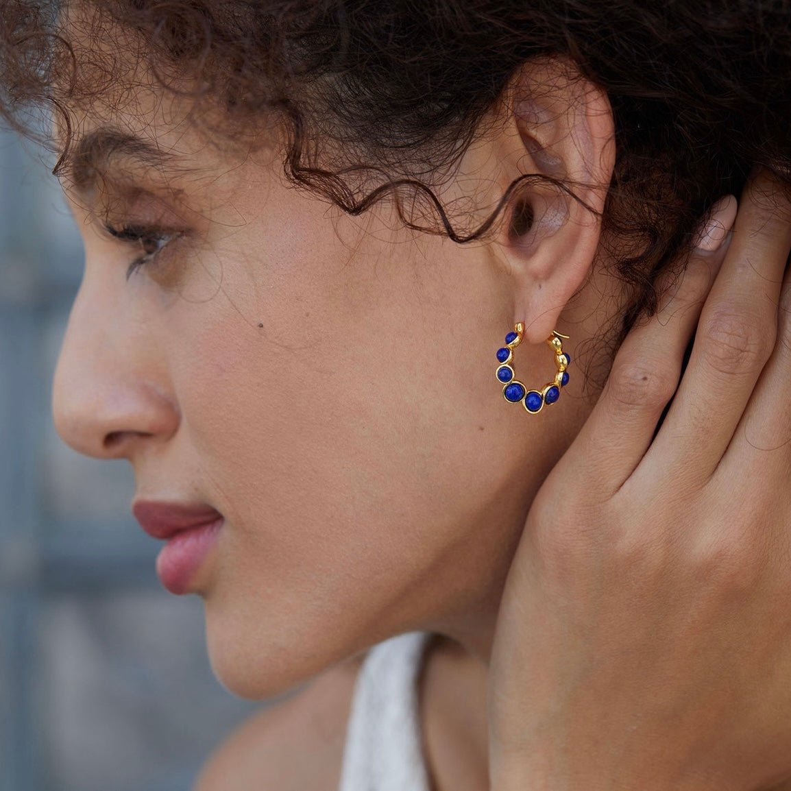 Model wearing the Awakened Time Céleste gold vermeil and lapis lazuli hoop earrings seen from a side view profile.