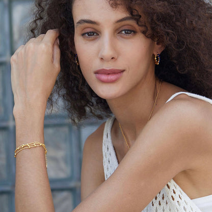 Portrait of a model wearing Awakened Time gold lapis lazuli hoop earrings and matching gold chain bracelet after her lover came into her body.