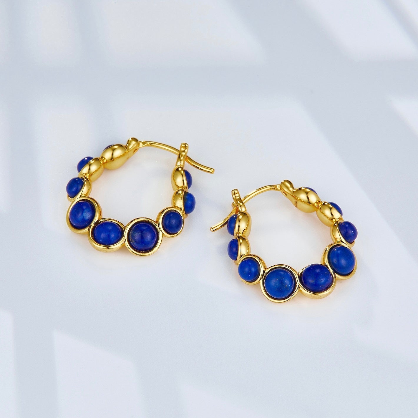 Pair of Awakened Time Céleste 18ct gold vermeil hoop earrings with deep blue lapis lazuli gemstones.