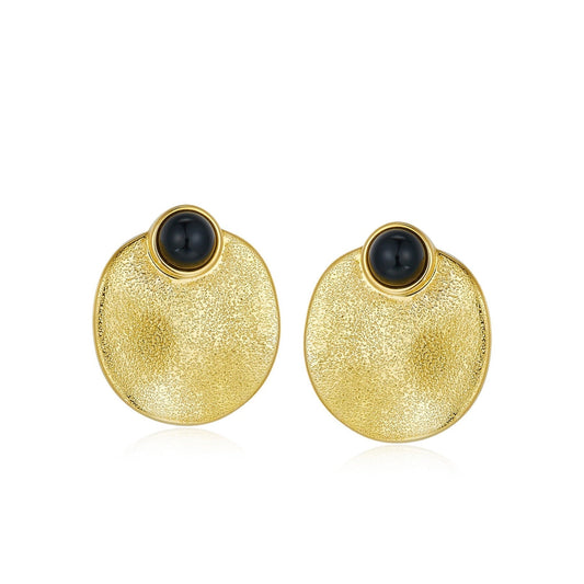 Pair of Awakened Time Eclipse stud earrings featuring polished round black onyx cabochons set atop textured dished gold circular discs on a white background.