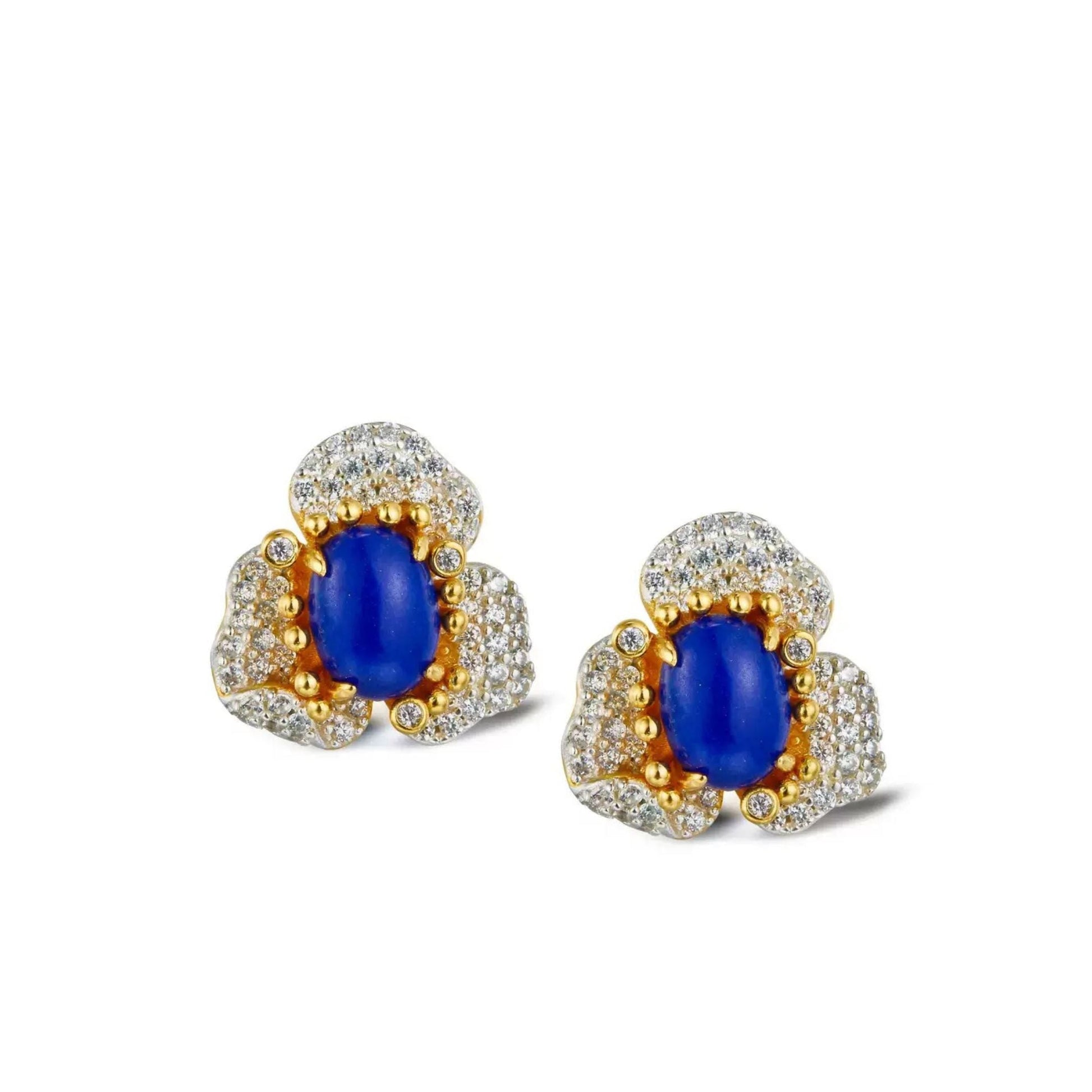 Pair of Awakened Time Fleur d’Écume stud earrings featuring oval blue lapis lazuli cabochons framed by gold prong detailing and sparkling pavé-set zirconia floral petals on a white background.