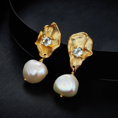 Awakened Time Fleur d’Or gold petal and freshwater pearl drop earrings displayed against a dark contrast background.