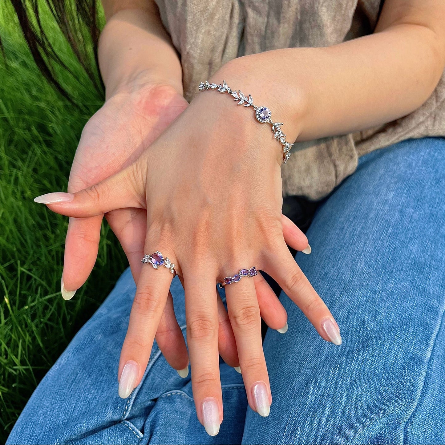 Awakened Time amethyst jewelry collection featuring floral gemstone rings and a sterling silver bracelet, styled as elegant nature-inspired jewelry for everyday wear.