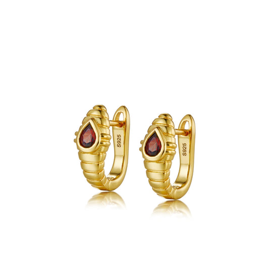 Pair of Awakened Time Gilded Viper gold huggie hoop earrings featuring a ribbed snake texture and bezel-set pear-shaped red garnet gemstones on a white background.
