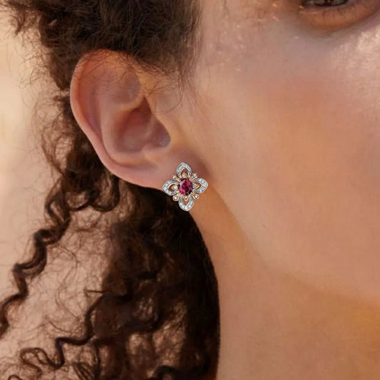 Close-up model shot featuring a woman with curly hair wearing the Awakened Time La Rosa di Firenze two-tone stud earring with a center red garnet stone.