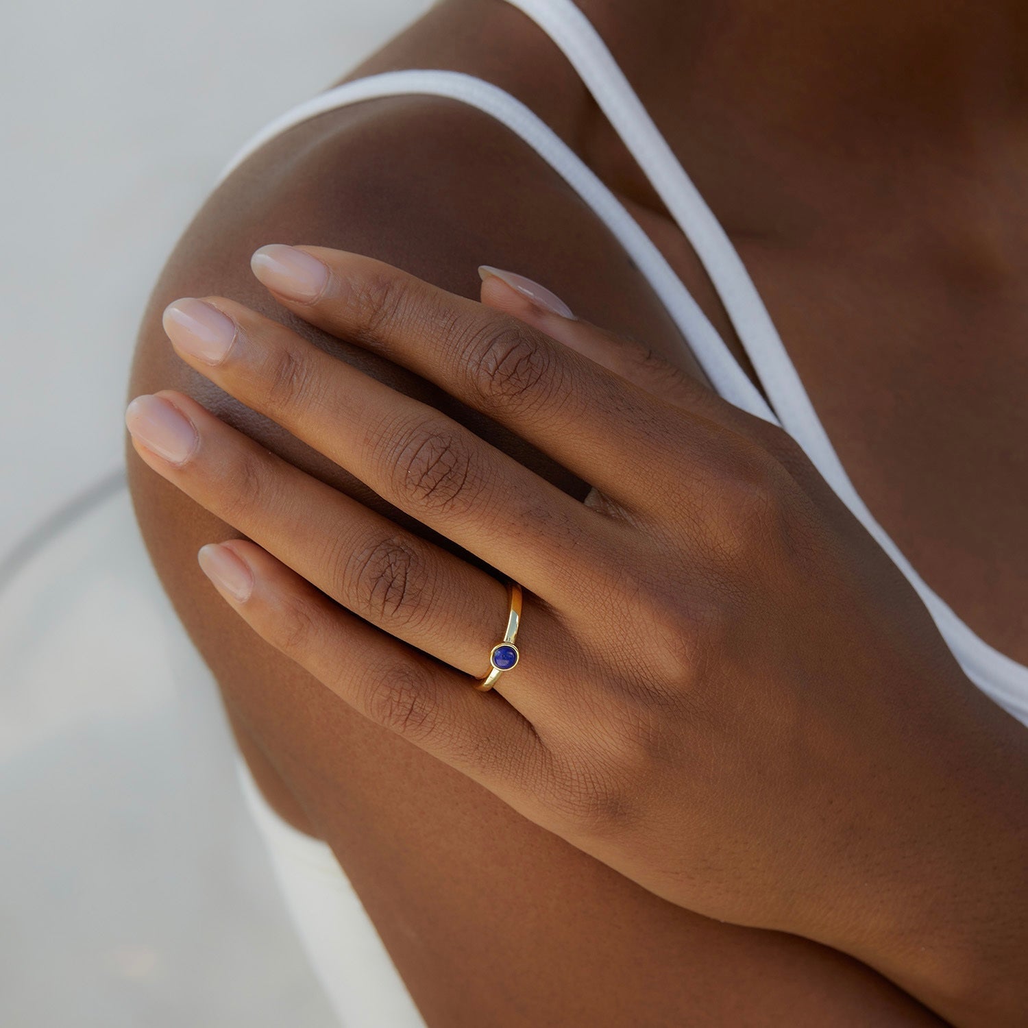 Model wearing a minimalist 18ct gold vermeil lapis lazuli ring on her shoulder, styled by Awakened Time as luxury everyday jewelry.