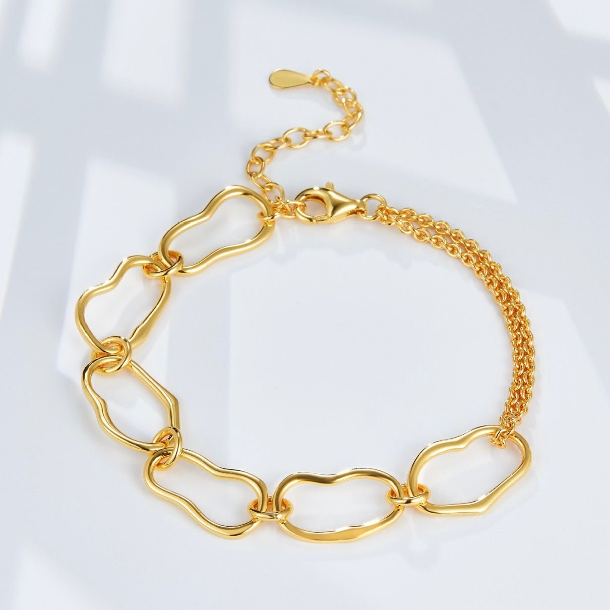 Flat lay product shot of the Awakened Time Liaison gold chain bracelet showcasing its unique irregular links, clasp, and double-strand extender chain on a clean white surface.