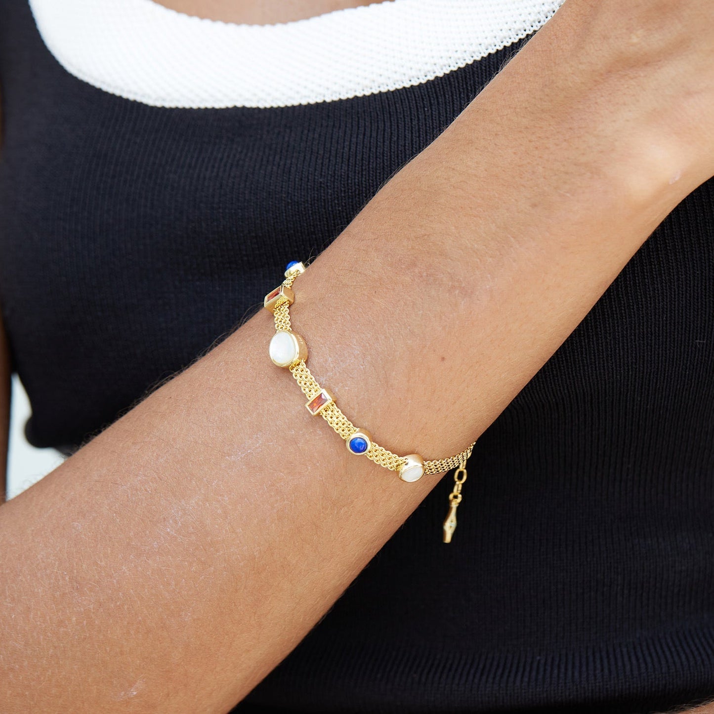 Woman wearing the Awakened Time Lumière Strand Bracelet crafted in 18ct gold vermeil with natural garnet, lapis lazuli, and mother-of-pearl gemstones.