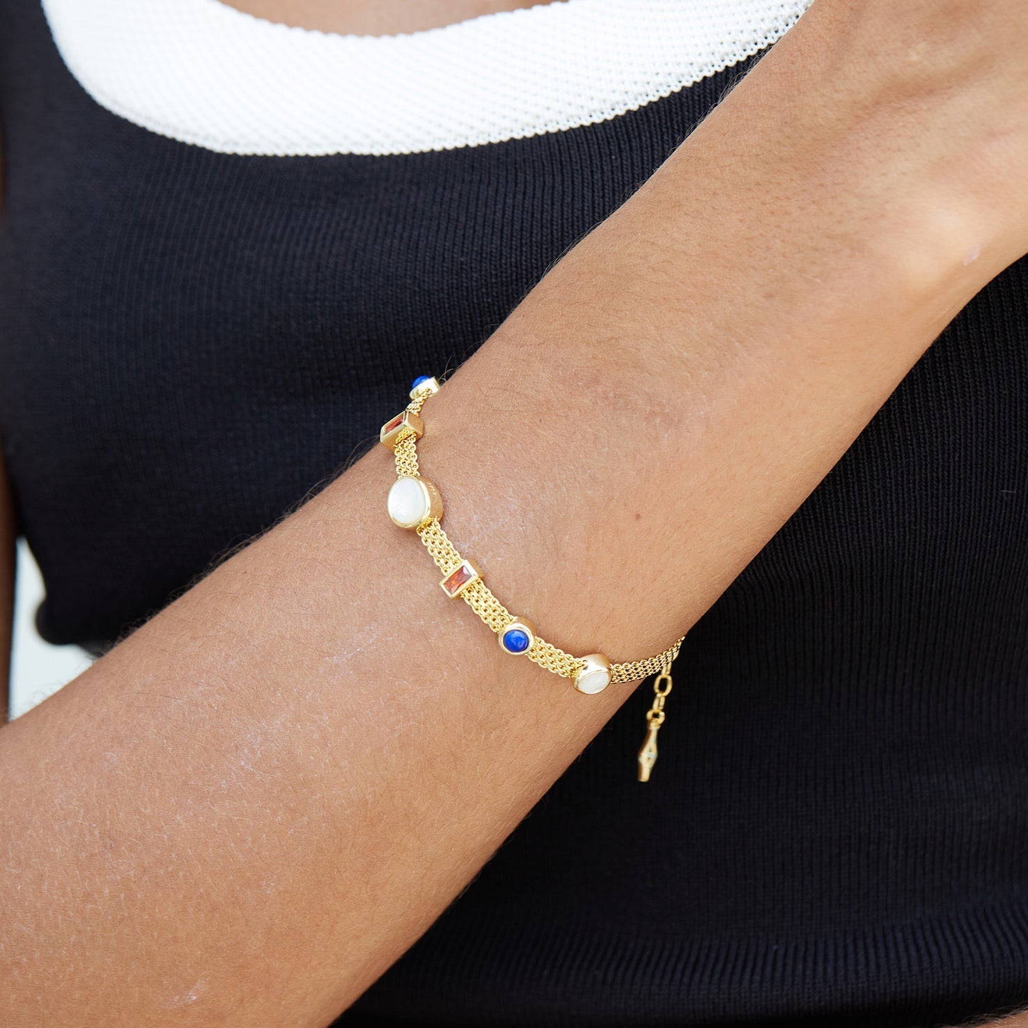 Woman wearing the Awakened Time Lumière Strand Bracelet crafted in 18ct gold vermeil with natural garnet, lapis lazuli, and mother-of-pearl gemstones.