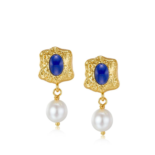 Pair of Awakened Time Noor drop earrings featuring textured gold frames centered with oval lapis lazuli stones suspending white freshwater pearls on a white background.