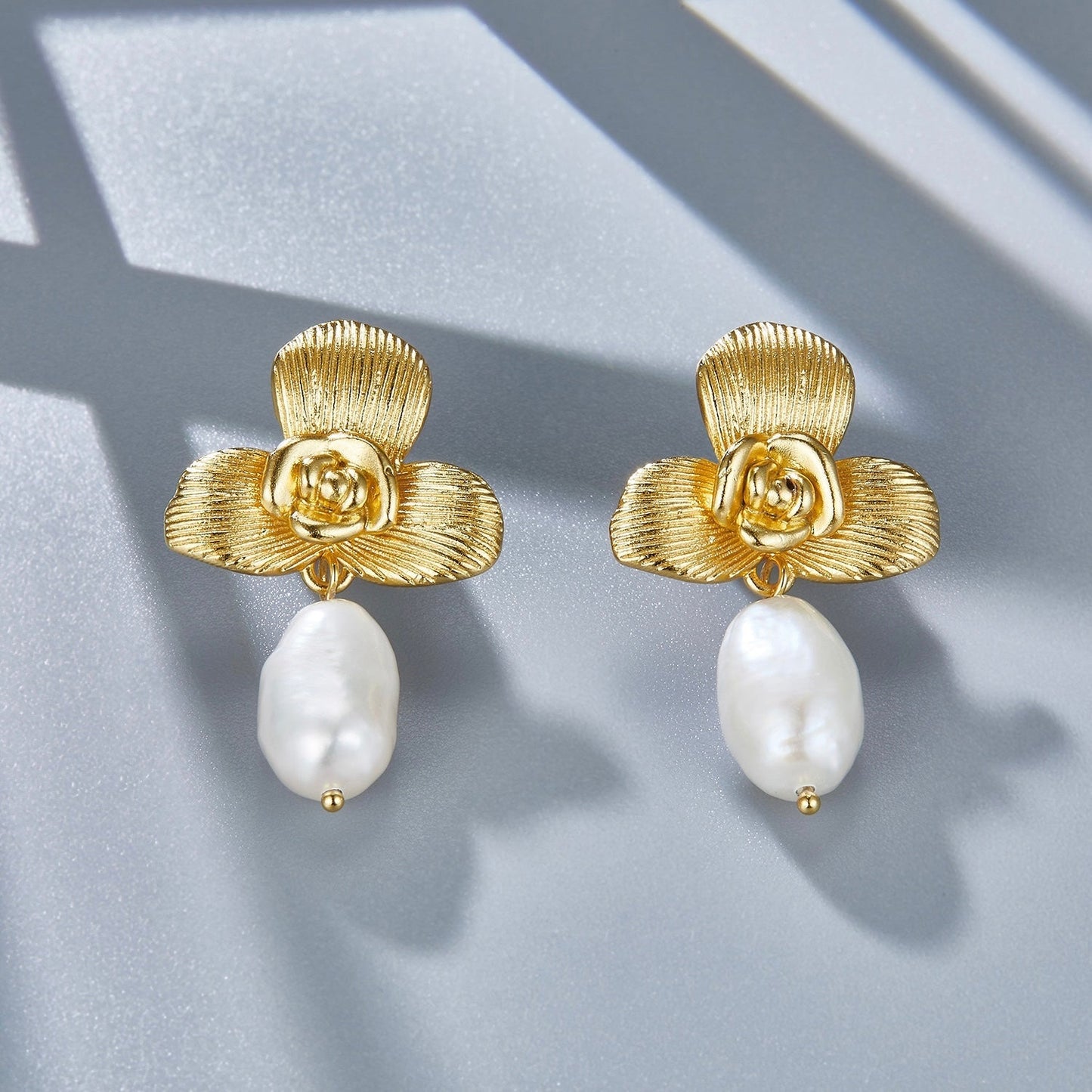 Both Awakened Time gold orchid pearl drop earrings displayed side by side with soft directional shadows.