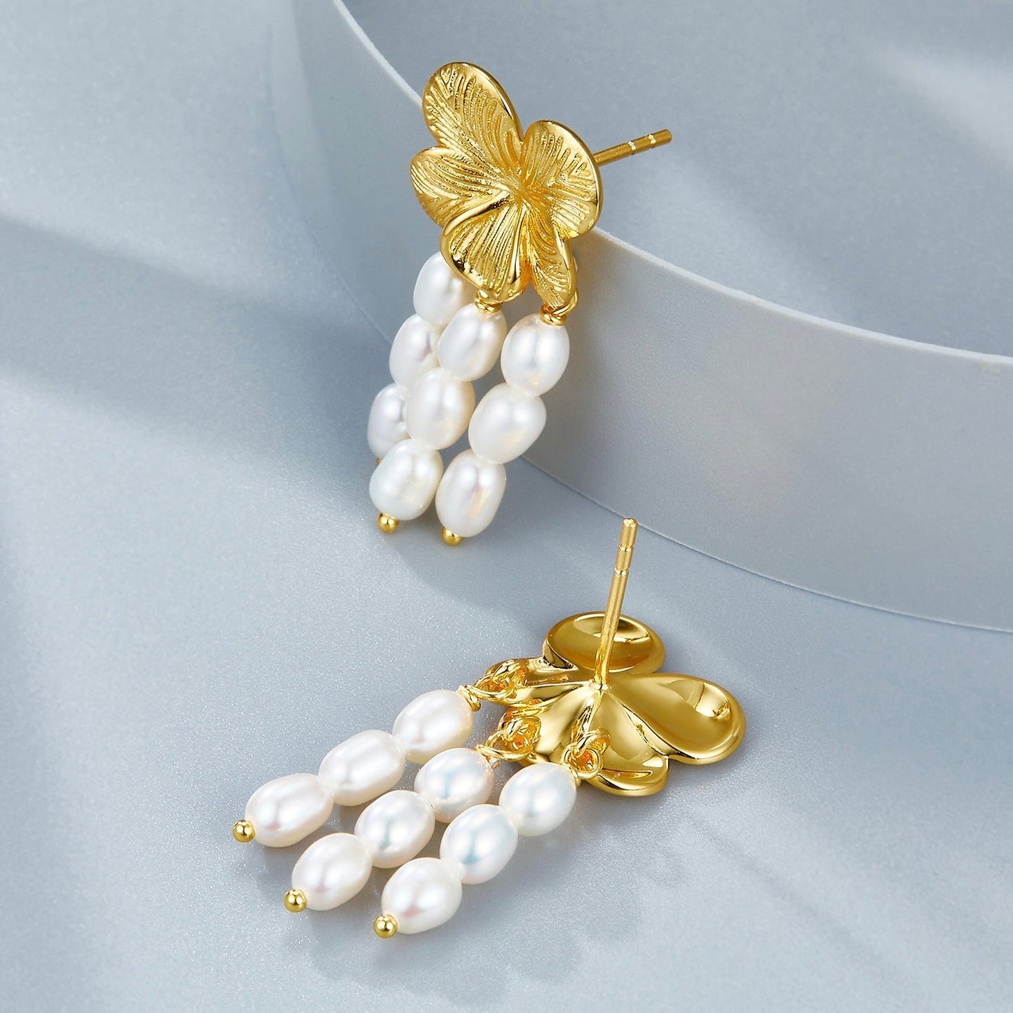 Front and back view of Awakened Time gold floral pearl cascade earrings displaying post backs and pearl strands.