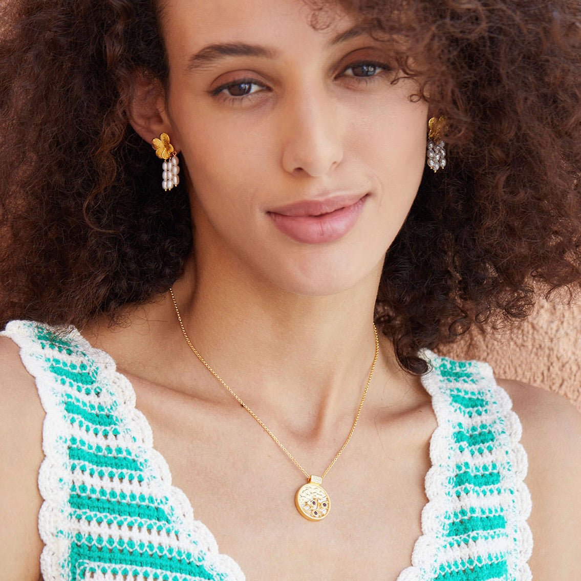 Model wearing a green crochet top paired with Awakened Time gold pearl cascade earrings and a matching pendant necklace.