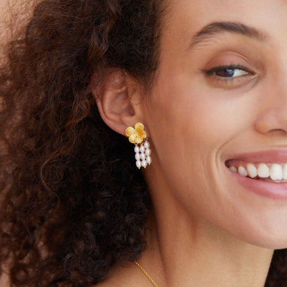 Model smiling while showcasing Awakened Time gold flower top and cascading freshwater pearl drop earrings.