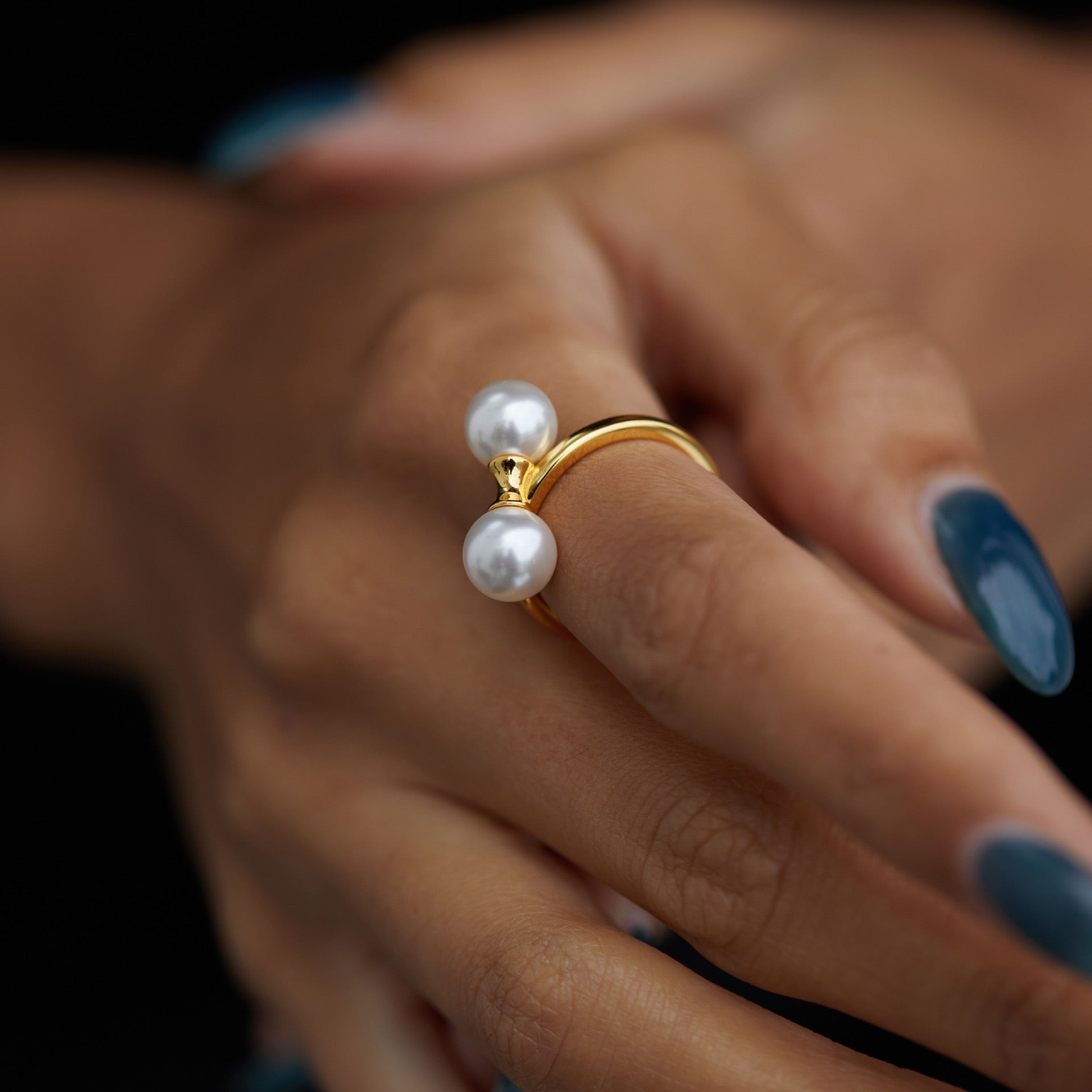 Close-up of a model's hand wearing The Petite Symétrie dual pearl gold ring by Awakened Time.