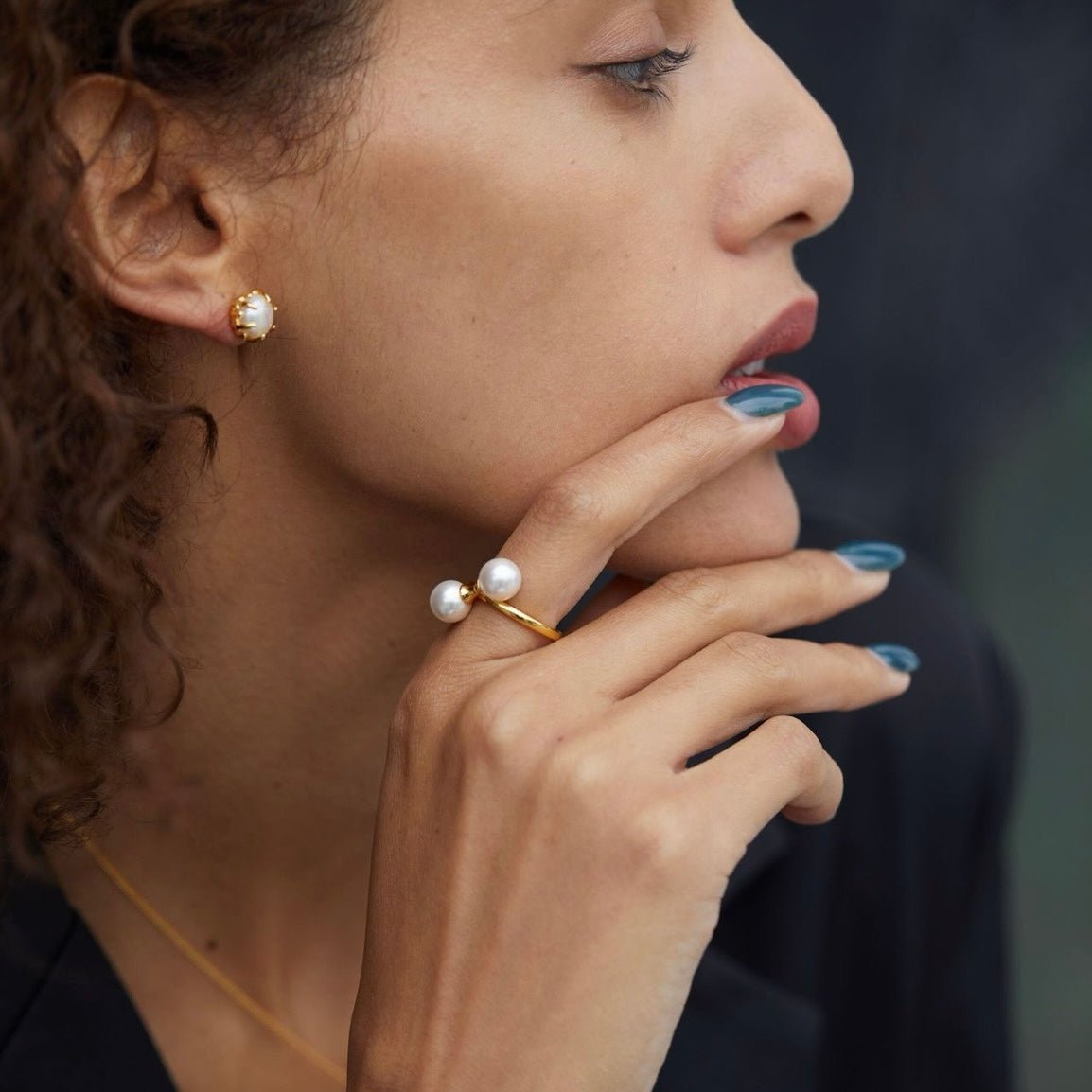 Side profile view of a model wearing The Petite Symétrie pearl ring and matching earrings by Awakened Time.