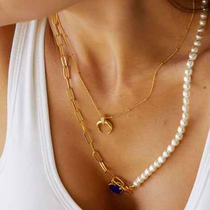 Model wearing the Awakened Time Radiant Horn Necklace in 18ct recycled gold vermeil paired with a pearl necklace.