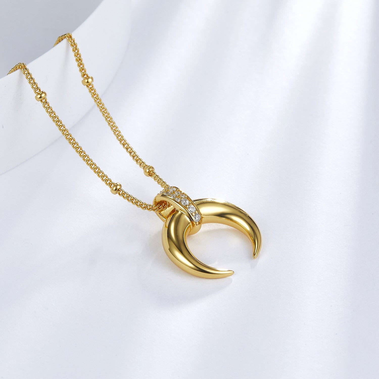 Angled detail view of the Awakened Time gold Radiant Horn pendant with sparkling gem bail.