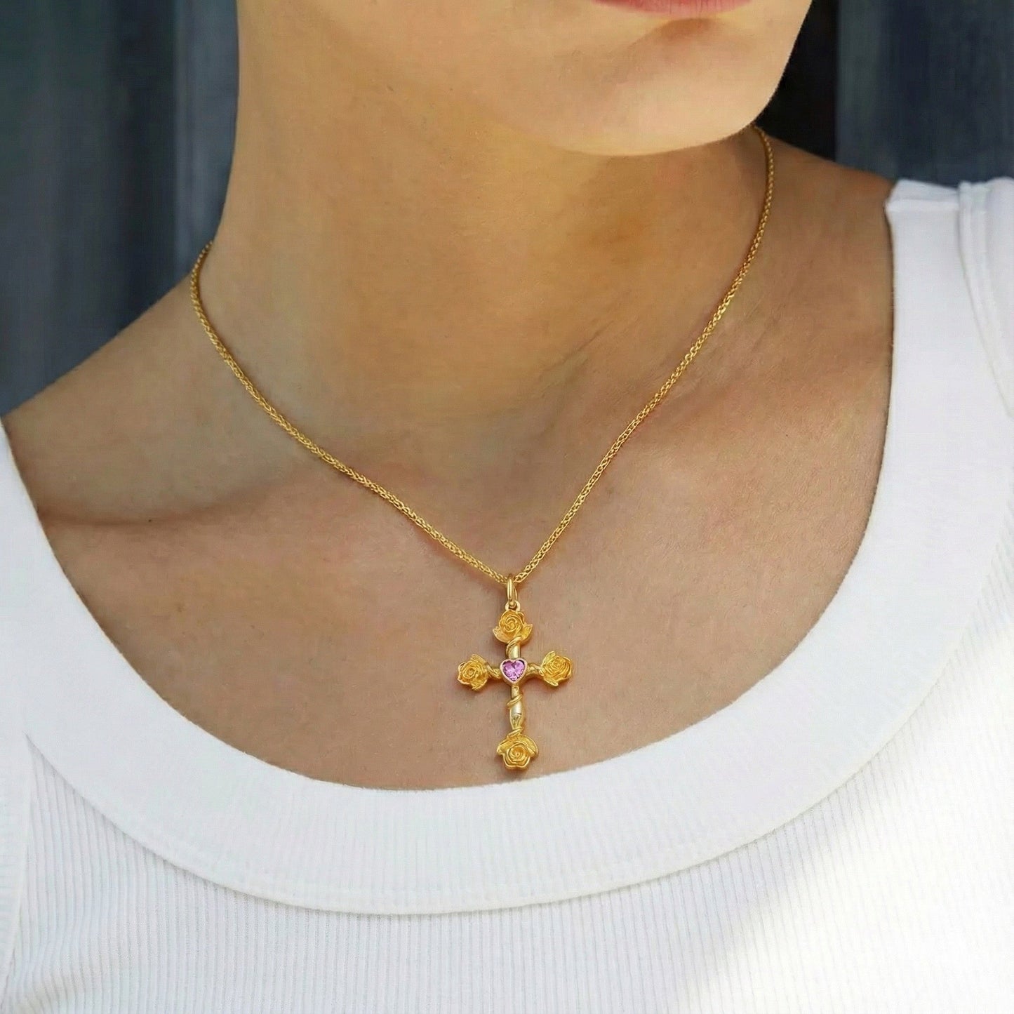 Model wearing the Awakened Time gold Rosevine Cross Necklace with a heart garnet pendant.