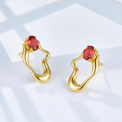 Awakened Time Rouge Wave gold earrings featuring red garnet gemstones and an elegant sculptural loop design.