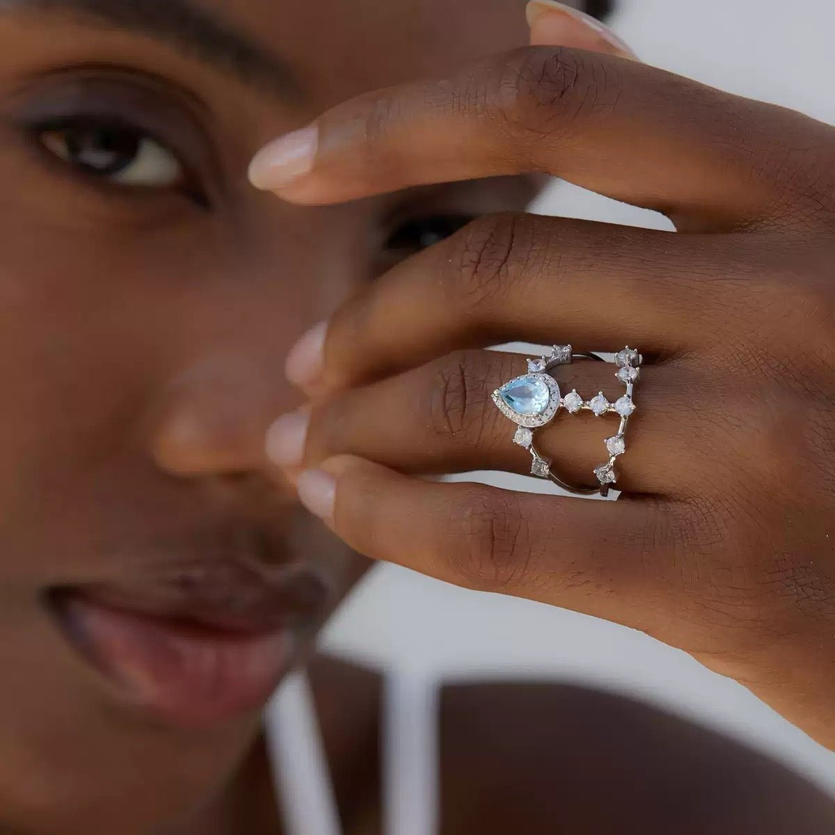 Awakened Time lifestyle photo of a woman wearing the Sky Vault Ring featuring a blue topaz and cubic zirconia in a white gold vermeil openwork setting.