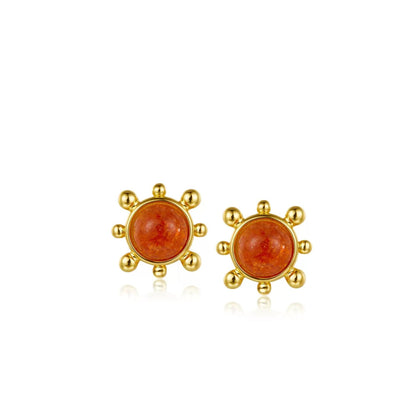 Pair of Awakened Time Solara stud earrings featuring round orange sunstones in a gold sunburst frame with beaded rays on a white background.