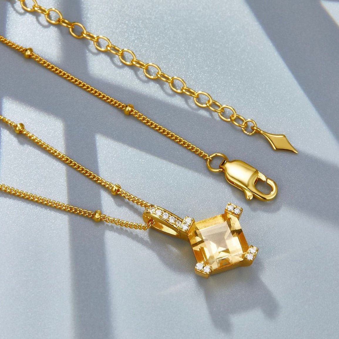 Close-up layout of the gold beaded chain, pendant bail, and clasp of the Awakened Time Stellar Frame necklace.