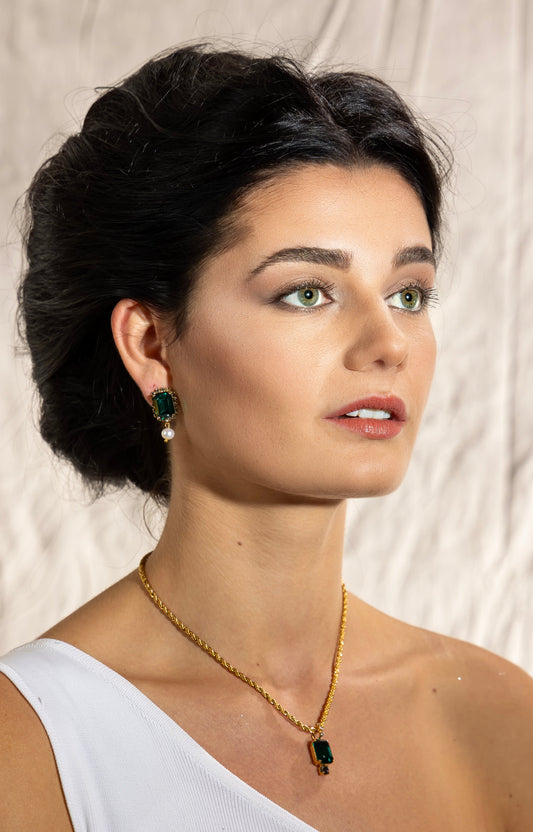Model wearing Awakened Time The Viper emerald crystal and freshwater pearl drop earrings with matching green pendant necklace.