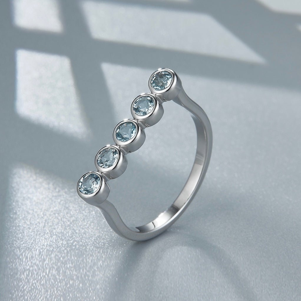 Awakened Time Timeline Ring featuring five natural blue topaz gemstones bezel-set along a graceful arc in 18ct recycled white gold vermeil over sterling silver.