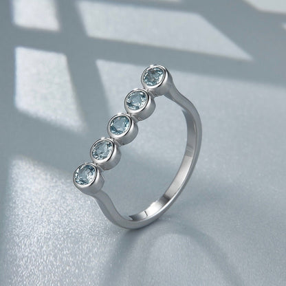 Awakened Time Timeline Ring featuring five natural blue topaz gemstones bezel-set along a graceful arc in 18ct recycled white gold vermeil over sterling silver.